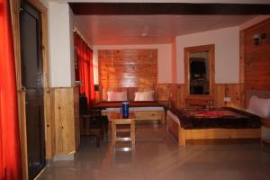达兰萨拉Vella Marina Group of hotels Mcleodgunj的一间卧室配有两张床、一张桌子和一张桌子