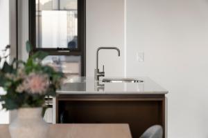 悉尼Urban Rest North Sydney Apartments的厨房柜台设有水槽和花瓶