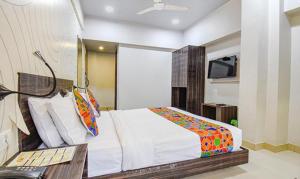 浦那FabHotel Rajdhani I Near Pune Railway Station的一间卧室配有一张床和一台电视