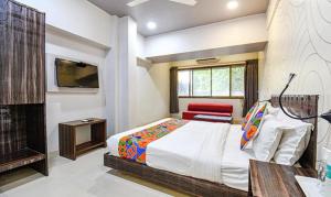 浦那FabHotel Rajdhani I Near Pune Railway Station的一间卧室配有一张床、一张桌子和一台电视