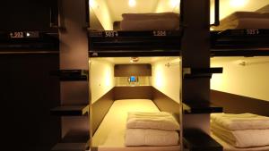 大阪Acro Capsule Hotel Namba Dotonbori的带三张双层床和镜子的客房