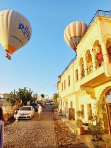 乌奇希萨尔Alice in Cappadocia的飞过街道的热气球,有楼房