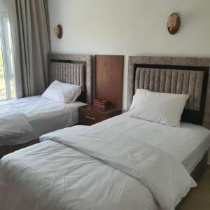 Salmahبيوت الخزام的配有白色床单的酒店客房内的两张床