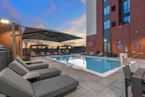 卡温顿Residence Inn by Marriott Atlanta Covington的一座带椅子和遮阳伞的游泳池位于大楼旁