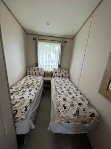 普尔赫利Hafan y Môr Holiday Park的小型客房 - 带2张床和窗户