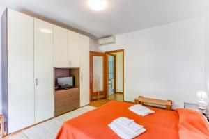 马里纳迪马萨Casa Arno 500m from beach的一间卧室配有橙色的床和电视