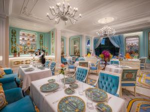 澳门Palazzo Versace Macau的一间带桌子和蓝色椅子的用餐室以及吊灯