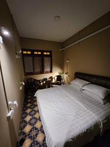 马六甲The Grand Bali Hotel的一间卧室配有一张大床和一张桌子及椅子