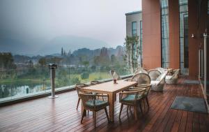 峨眉山峨眉山恒邦艾美度假酒店的一个带大窗户的阳台,配有一张木桌子和椅子