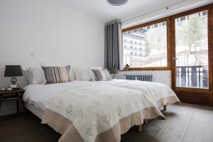 夏蒙尼-勃朗峰Le Brevent 3 Apartment的卧室配有一张大白色床和窗户