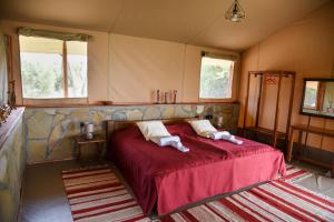 AitongMara Siria Tented Camp & Cottages的一间卧室配有红色的床和两个枕头