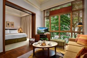 新加坡Treetops Executive Residences的一间带一张床的房间和一间带桌子的客厅