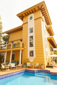 马拉加Hotel Boutique Villa Lorena by Charming Stay Adults Recommended的一座黄色的房子,前面有一个游泳池