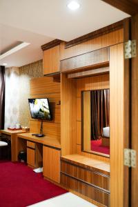 DukuGrand Buana Lestari Hotel的一间酒店客房,房间内设有一张桌子和一台电视机