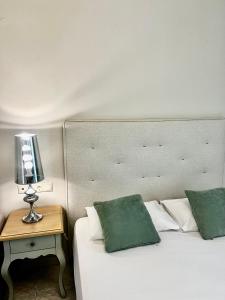 奈德里Eva beach hotel的一张带两个绿色枕头的床和一张桌子上的台灯