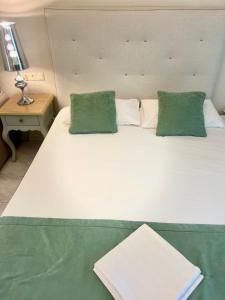 奈德里Eva beach hotel的一张带两个绿色枕头的大型白色床