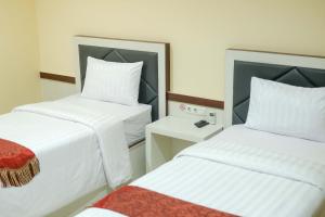 DukuGrand Buana Lestari Hotel的酒店客房设有两张床和一张桌子。