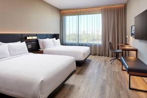 里奇兰AC Hotel by Marriott Jackson Ridgeland的酒店客房配有两张床和一张书桌