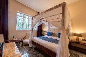 LimuruMuthu Sovereign Suites & Spa, Limuru Road, Nairobi的一间卧室设有天蓬床和窗户。