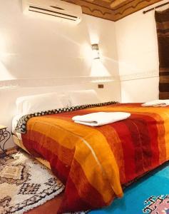 Aït Idaïr拉菲布勒杜达笛斯宾馆的一间卧室配有一张带彩色毯子的床