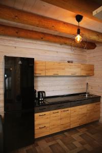 ŽaliukaiŽaliūkių pirtis的厨房配有黑色冰箱和木墙