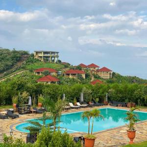 纳库鲁CAPELLA RESORT (ELEMENTAITA, KENYA)的一座度假村游泳池,其背景是度假村