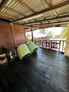 丰盛港Warisan Homestay Anjung的门廊铺有木地板,配有2把绿色椅子