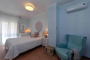 Praia VerdePraia Verde Villa - 6/8 pessoas的一间卧室配有一张床和一张蓝色椅子