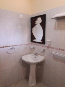 罗安达Agentour Guesthouses的一间带水槽的浴室和墙上的照片
