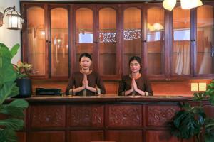 万象Phongsavath Boutique Hotel的两个坐在酒吧里冥想的女人