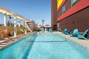 埃尔帕索埃尔帕索机场希尔顿欣庭套房酒店的一座带蓝色椅子的游泳池和一座建筑