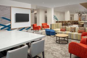 奥兰多Hilton Garden Inn Orlando Downtown的一间设有桌椅和电视的等候室