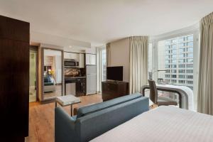 纽约曼哈顿中城时代广场南部惠庭套房酒店的一间卧室配有一张床、一张沙发和一台电视。