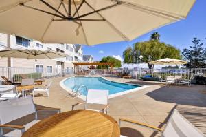 奥克兰奥克兰海滨希尔顿惠庭套房酒店的一个带桌椅和遮阳伞的游泳池