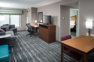 斯科基芝加哥北岸希尔顿旅馆&套房酒店的酒店客房设有一张沙发和一张带电视的书桌。