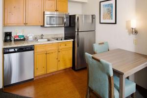 阿尔伯克基阿尔伯克基住宅区希尔顿惠庭套房酒店的厨房配有桌子和不锈钢冰箱。