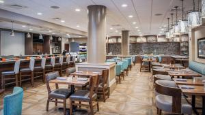 西棕榈滩DoubleTree by Hilton Hotel West Palm Beach Airport的一间带木桌椅的餐厅和一间酒吧