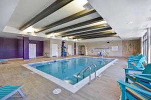 佩里斯堡Home2 Suites by Hilton Perrysburg Levis Commons Toledo的大楼内一个带蓝色椅子的大型游泳池