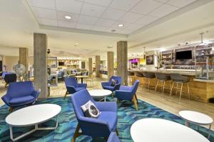 佩里斯堡Home2 Suites by Hilton Perrysburg Levis Commons Toledo的大堂设有蓝色桌椅,酒吧