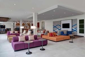 麦迪逊Hilton Garden Inn Madison Huntsville Airport的大堂设有紫色和橙色的沙发和桌子
