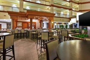 奥本希尔斯Embassy Suites by Hilton Auburn Hills的一间带桌椅的餐厅和一间酒吧