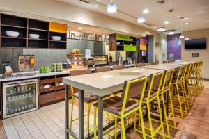 圣安东尼奥Home2 Suites by Hilton San Antonio Downtown - Riverwalk, TX的一间设有一张大桌子和黄色椅子的自助餐厅