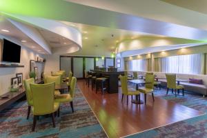 里士满里士满南希尔顿恒庭酒店的一间设有黄色桌椅的餐厅和一间酒吧