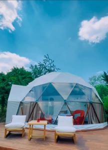 萨潘贾Phalesia Glamping Otel的甲板上配有桌椅的帐篷