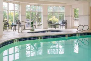 莱克奥斯韦戈Hilton Garden Inn Portland Lake Oswego的房屋内带桌椅的游泳池