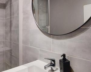 罗阿纳ArtGrey * Idéal Pro * Roanne Secteur Gare et rue piétonnes的一间带水槽和圆镜子的浴室