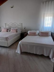 RicciaIl Riccio home & relax的卧室设有两张床,拥有白色的墙壁和木地板