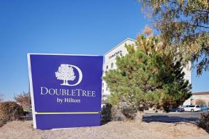 丹佛DoubleTree by Hilton Denver International Airport, CO的一座有树的建筑前面的标志