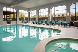 奥斯汀Embassy Suites by Hilton Austin Central的一个带蓝色椅子和窗户的大型游泳池