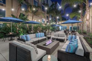 科默斯洛杉机希尔顿逸林酒店的一个带沙发和桌子及蓝色遮阳伞的庭院